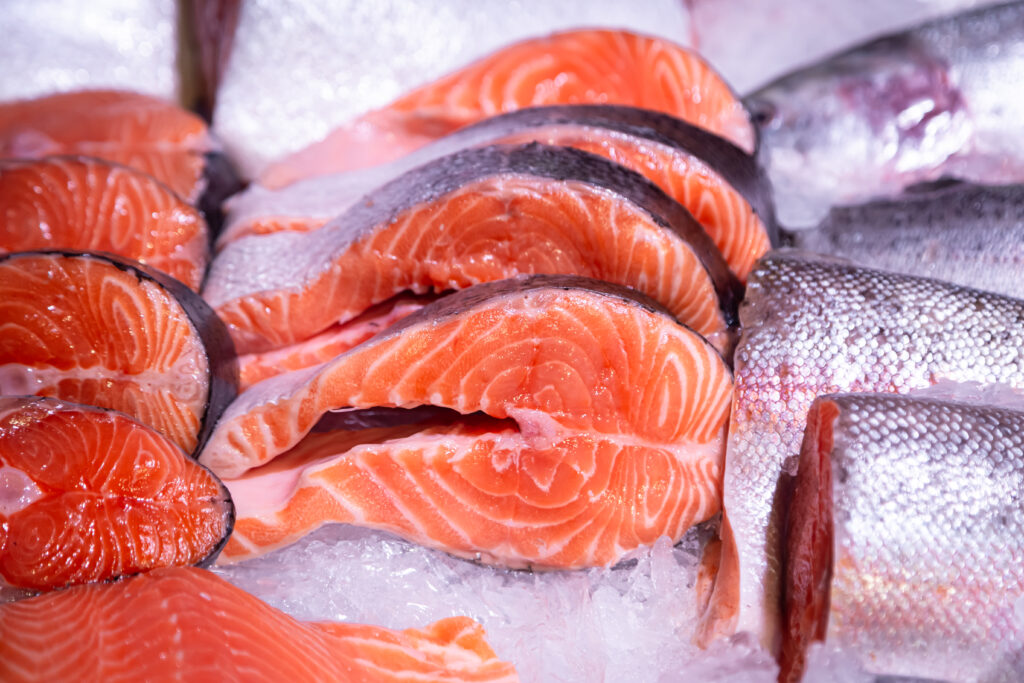Pieces of raw steak from fresh salmon lying on the ice counter at the fish market.
